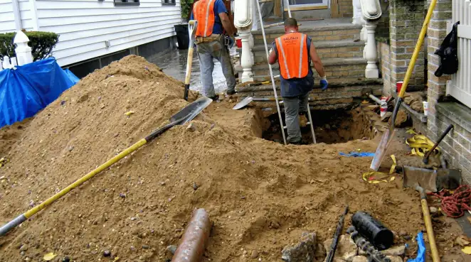 Contractors performing foundation protection and exterior drainage excavation near residential home steps in El Paso, TX