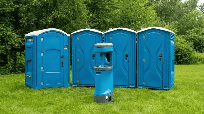Four blue portable toilets and a matching hand washing station on grass near trees, a common sight at local outdoor events in El Paso, TX